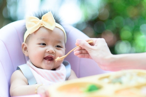 Ibu yang sedang menyuapi anak laki-laki makan