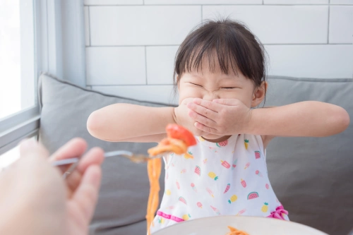 Anak menutup mulut saat sedang diberi makan.