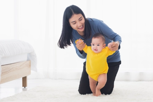 Ibu sedang mengajarkan bayi berjalan.