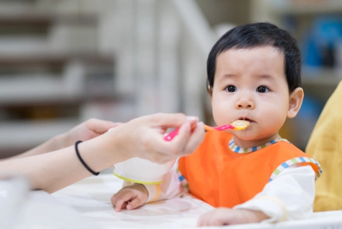 Ibu menyuapi bayi dengan sendok 