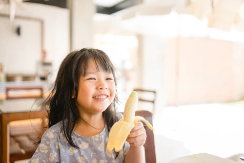 Anak sedang makan buah pisang.