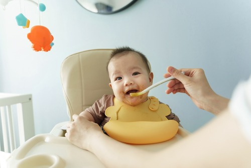 Bayi sedang makan di atas baby chair.