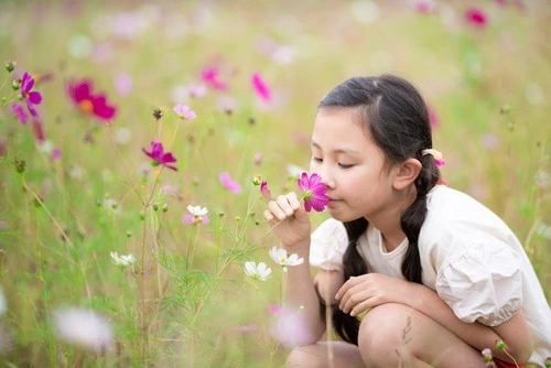 Anak perempuan mencium bunga