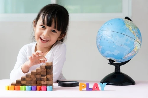 Anak perempuan sedang bermain balok susun.